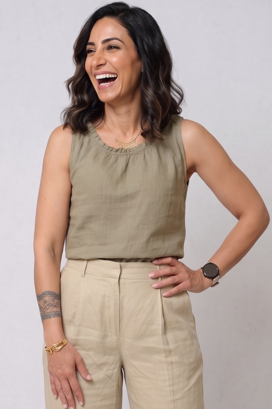 A woman modeling a sleeveless olive green top and beige wide-leg trousers against a light gray studio background.