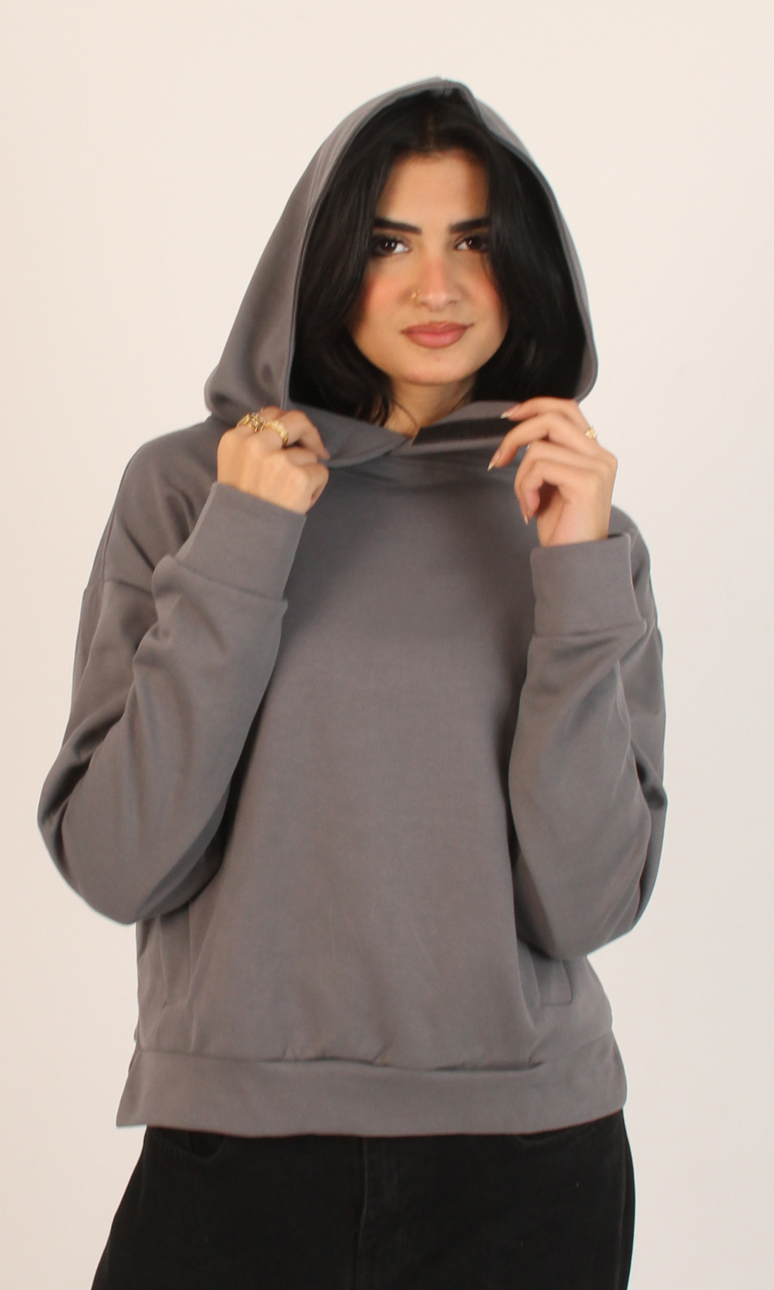 Woman wearing a gray hoodie against a plain background