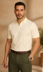 Man wearing a white polo shirt and green pants against a beige background